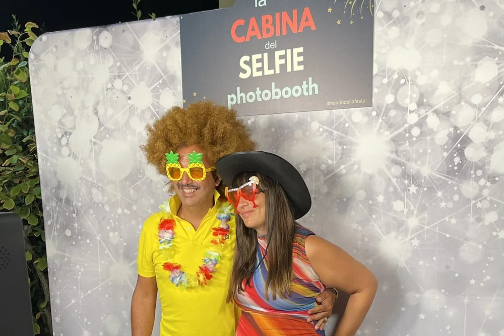 Due ospiti con parrucca e occhiali davanti al fondale del photobooth